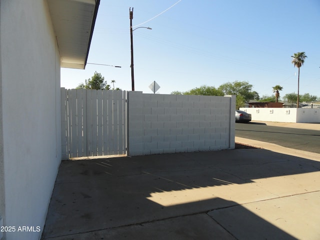 view of parking with fence and a gate