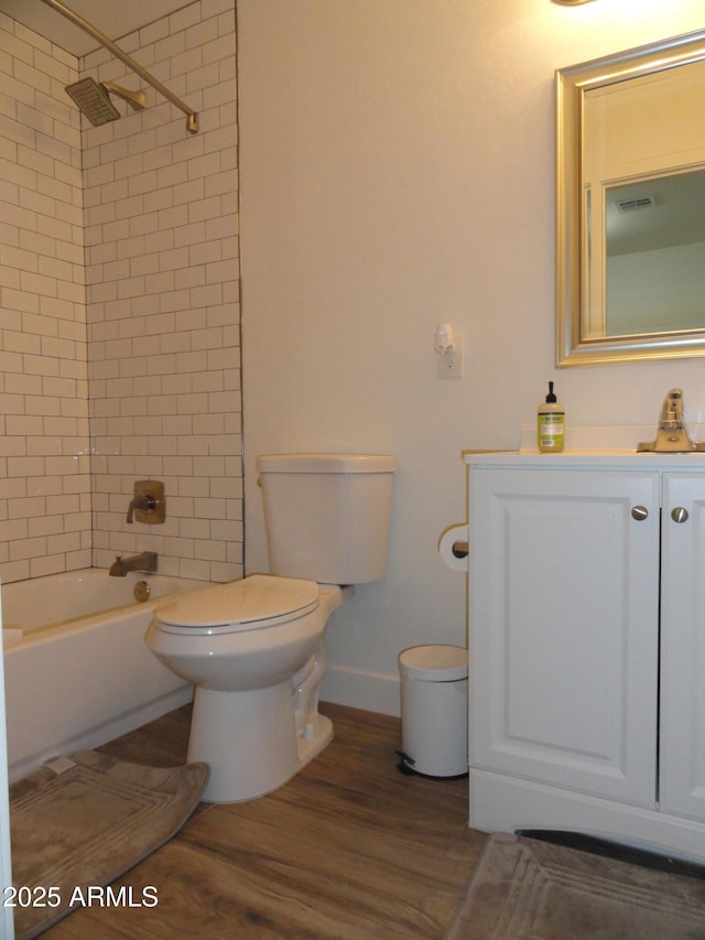 bathroom featuring wood finished floors, toilet, baseboards, shower / tub combination, and vanity