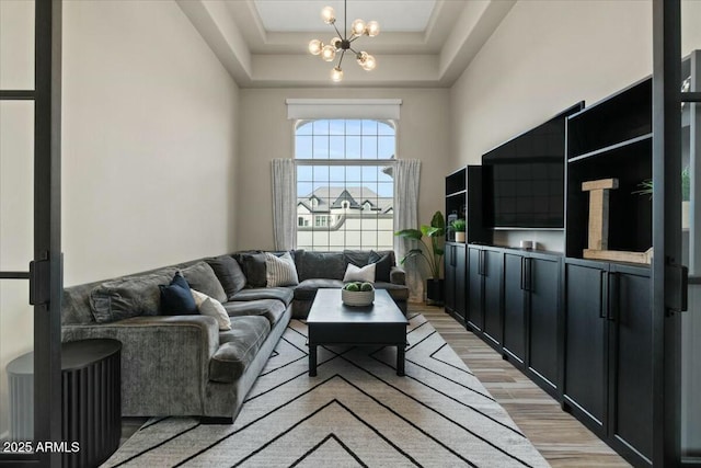 living room with a chandelier, a high ceiling, and a tray ceiling