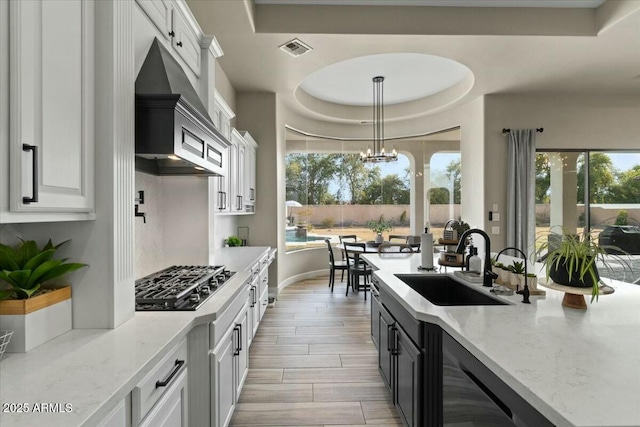 kitchen featuring sink, white cabinetry, a tray ceiling, and stainless steel gas stovetop