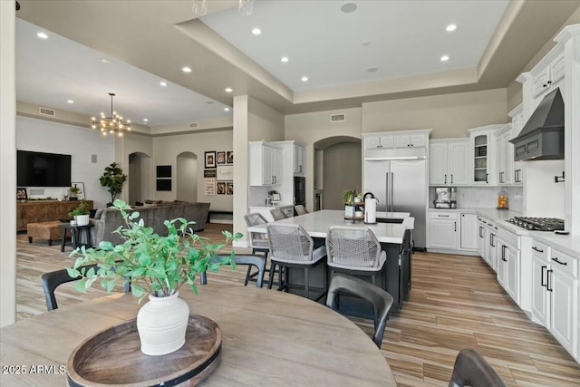 dining area with a high ceiling, a raised ceiling, and a notable chandelier