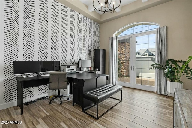 office area with a healthy amount of sunlight, a chandelier, a towering ceiling, and french doors