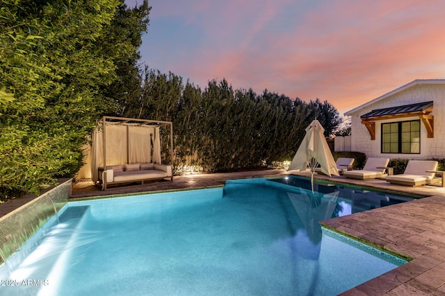 pool at dusk with a patio area