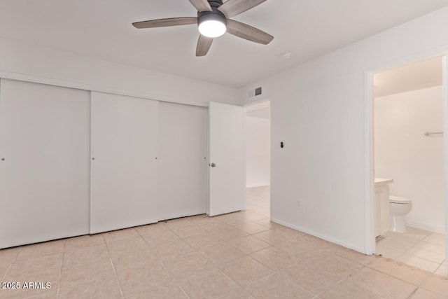unfurnished bedroom featuring visible vents, a closet, ceiling fan, light tile patterned floors, and ensuite bath