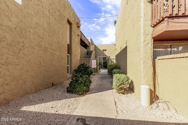 view of side of home featuring fence and stucco siding