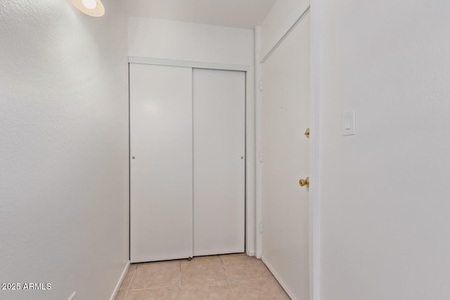 corridor featuring baseboards and light tile patterned flooring