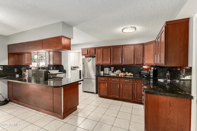6426 W Lamar Rd, Glendale, AZ 85301 - kitchen with freestanding refrigerator, washing machine and clothes dryer, a peninsula, tasteful backsplash, and a textured ceiling
