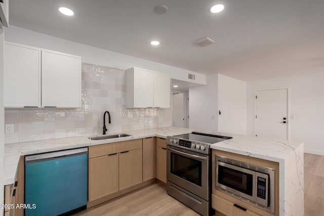 2443 E Randall Dr, Tempe, AZ 85288 - kitchen with stainless steel appliances, a sink, a peninsula, light wood-style flooring, and backsplash