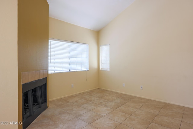 unfurnished living room with light tile patterned floors, vaulted ceiling, and a tiled fireplace