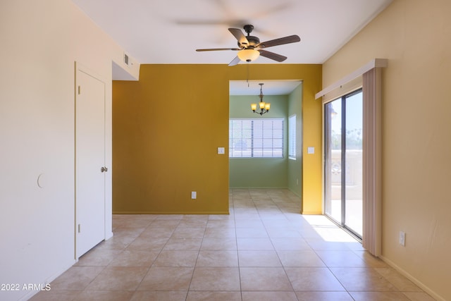 tiled spare room with ceiling fan with notable chandelier