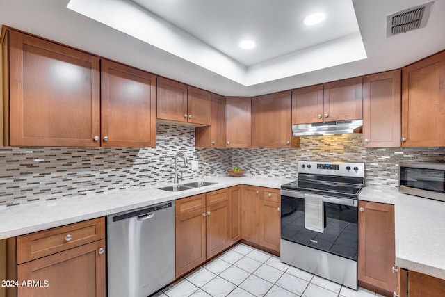 kitchen with stainless steel appliances, sink, backsplash, light tile patterned flooring, and a tray ceiling