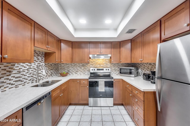 kitchen with stainless steel appliances, decorative backsplash, sink, a raised ceiling, and light tile patterned floors