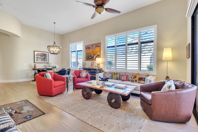 living room featuring ceiling fan with notable chandelier and light hardwood / wood-style floors