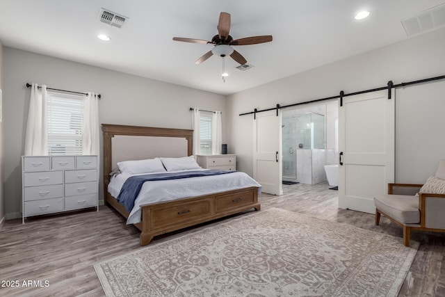 19436 W Windsor Ave, Buckeye, AZ 85396 - bedroom with a barn door, light wood-style flooring, connected bathroom, recessed lighting, and ceiling fan