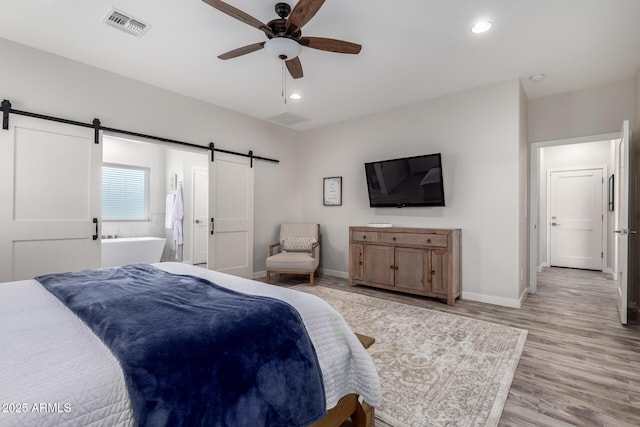19436 W Windsor Ave, Buckeye, AZ 85396 - bedroom with a barn door, light wood-style floors, baseboards, recessed lighting, and ensuite bath