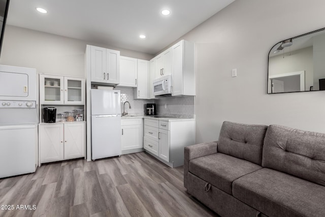 19436 W Windsor Ave, Buckeye, AZ 85396 - kitchen featuring white appliances, stacked washer and clothes dryer, open floor plan, light countertops, and white cabinetry
