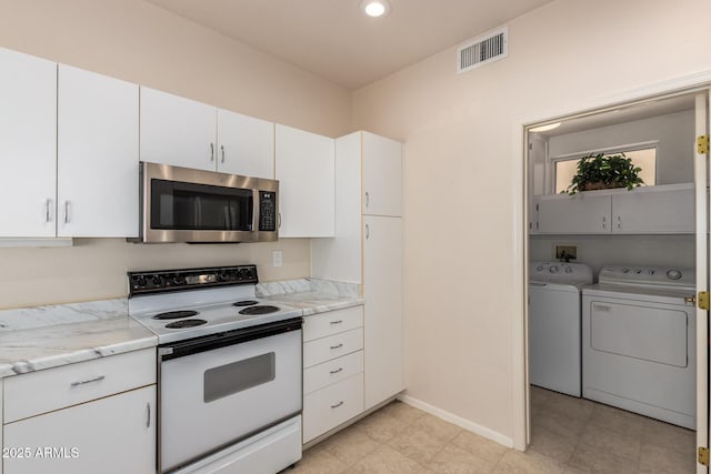 kitchen featuring white electric stove, white cabinets, washer and clothes dryer, stainless steel microwave, and light stone counters