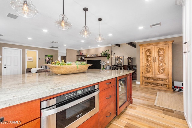 kitchen with ornamental molding, light hardwood / wood-style flooring, hanging light fixtures, and beverage cooler