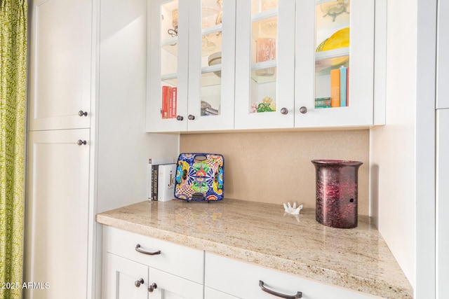 bar with white cabinetry and light stone counters