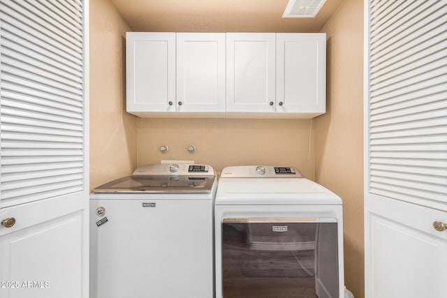 laundry room featuring washer and dryer and cabinets