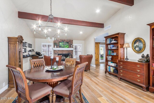 dining space with light hardwood / wood-style flooring, beamed ceiling, and a fireplace