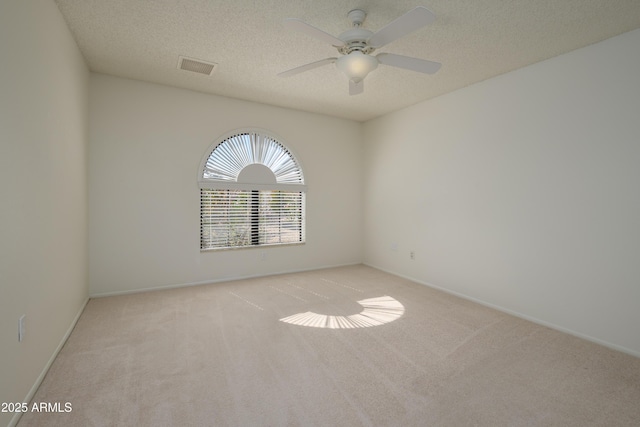 empty room with ceiling fan, light colored carpet, and a textured ceiling