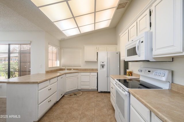 kitchen with lofted ceiling, light tile patterned floors, white appliances, sink, and white cabinetry