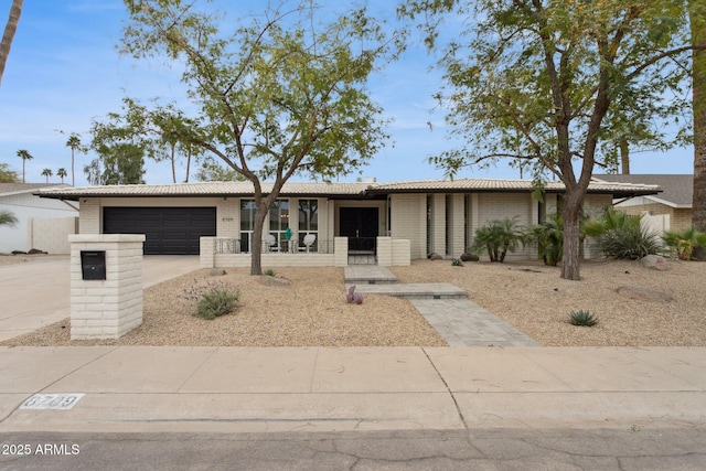 view of front facade featuring an attached garage, driveway, a porch, and brick siding