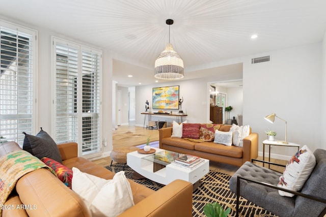 living room with recessed lighting, visible vents, baseboards, and wood finished floors