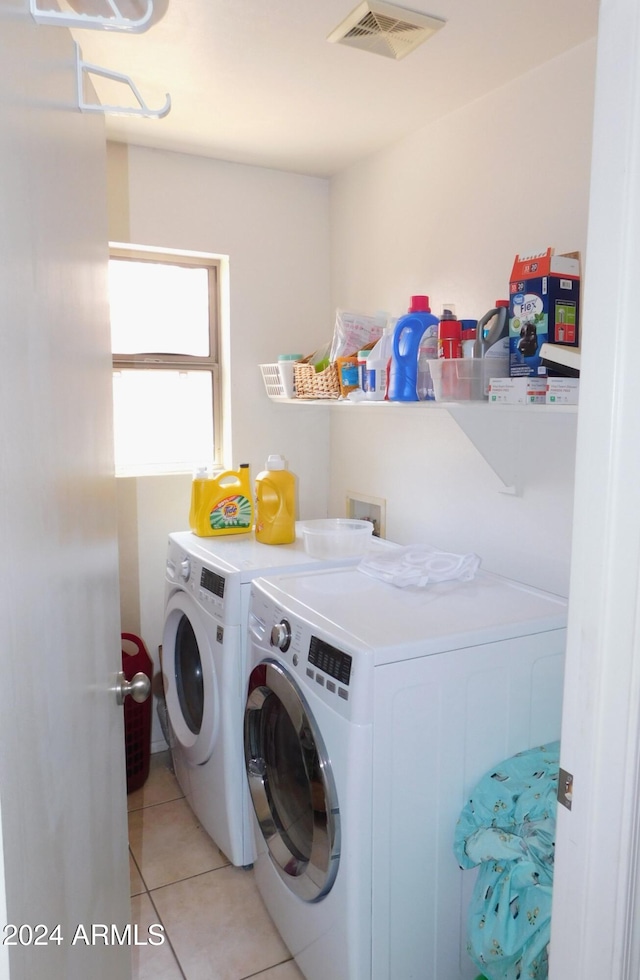 laundry area with washing machine and clothes dryer and light tile patterned floors