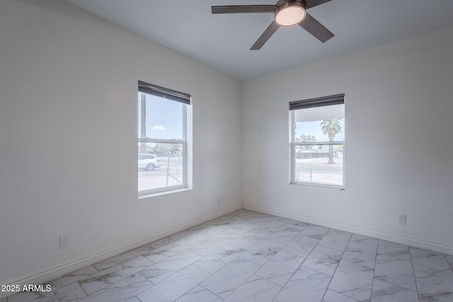 empty room with baseboards, ceiling fan, and marble finish floor