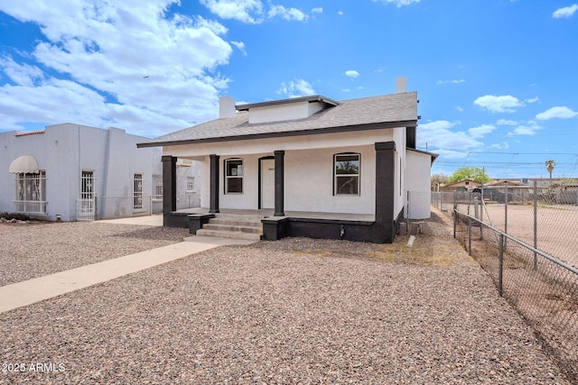 bungalow with stucco siding, covered porch, a chimney, and fence