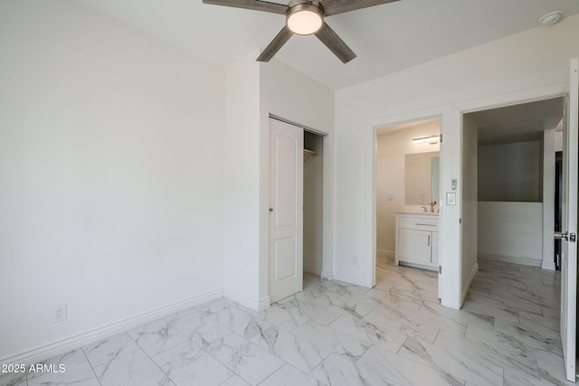 unfurnished bedroom with ceiling fan, baseboards, a closet, marble finish floor, and ensuite bath
