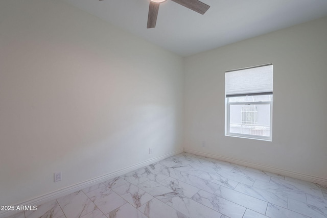spare room featuring baseboards, ceiling fan, and marble finish floor