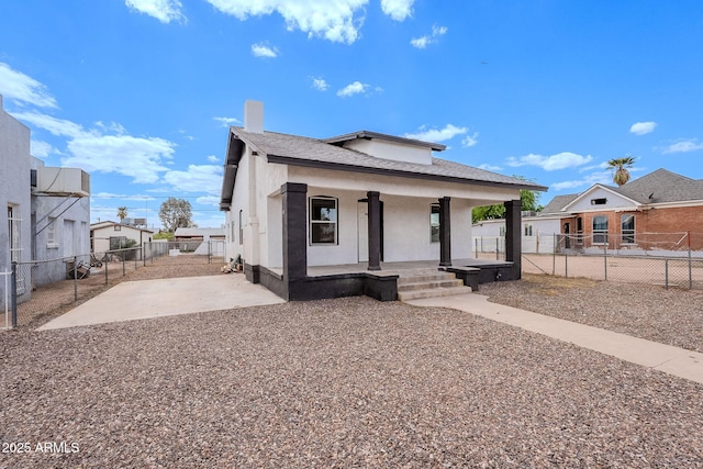 bungalow featuring covered porch, a fenced backyard, roof with shingles, stucco siding, and a chimney