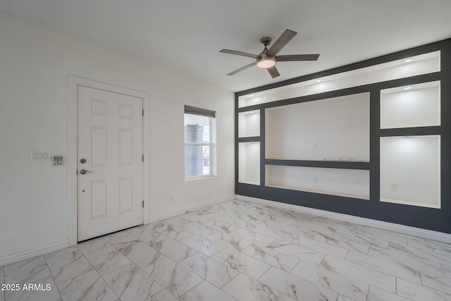 unfurnished room with a ceiling fan, baseboards, and marble finish floor