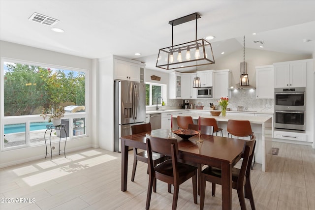 dining area featuring visible vents, lofted ceiling, and plenty of natural light