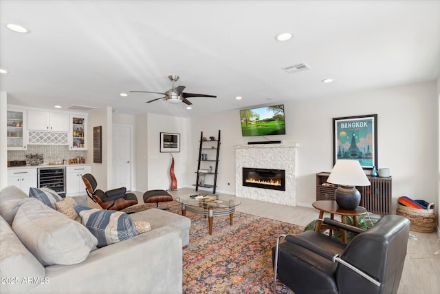 living room with visible vents, beverage cooler, a glass covered fireplace, recessed lighting, and a bar