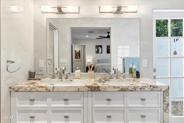 full bath with a sink, tile walls, ensuite bath, and double vanity