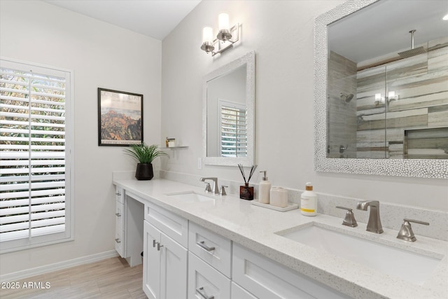 bathroom with a sink, baseboards, a stall shower, and double vanity