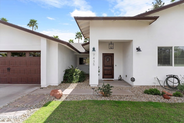 doorway to property featuring stucco siding, concrete driveway, and an attached garage