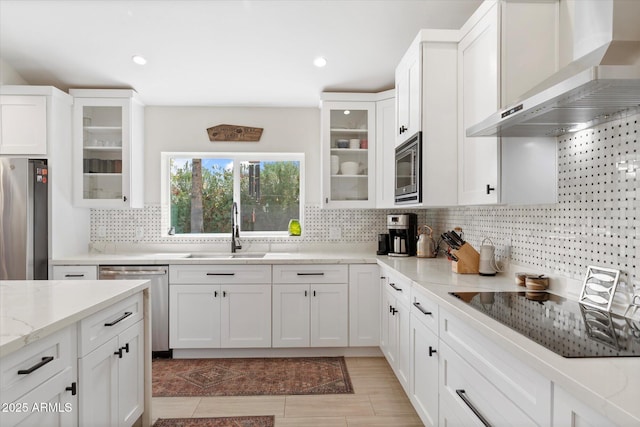 kitchen with white cabinetry, wall chimney exhaust hood, appliances with stainless steel finishes, and a sink