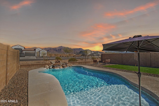 pool at dusk with a fenced in pool, a patio area, a fenced backyard, and a mountain view