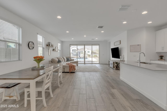 living area with light wood-type flooring, visible vents, and recessed lighting