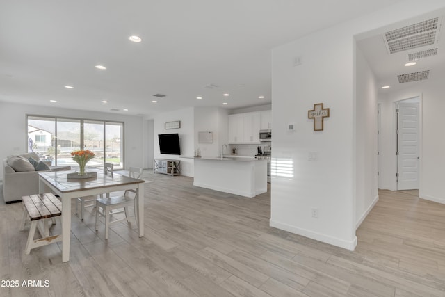 dining room featuring light wood finished floors, baseboards, visible vents, and recessed lighting