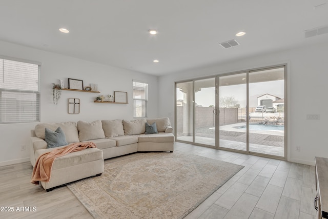 living area with light wood-style flooring, visible vents, baseboards, and recessed lighting