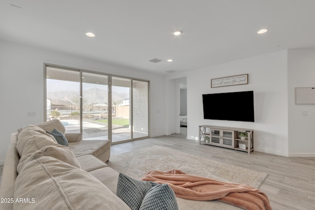 living room with light wood finished floors, visible vents, baseboards, and recessed lighting