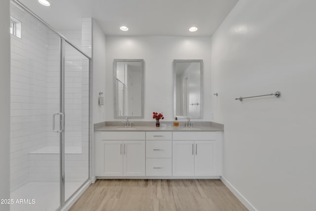 full bath featuring wood finished floors, a sink, and a shower stall