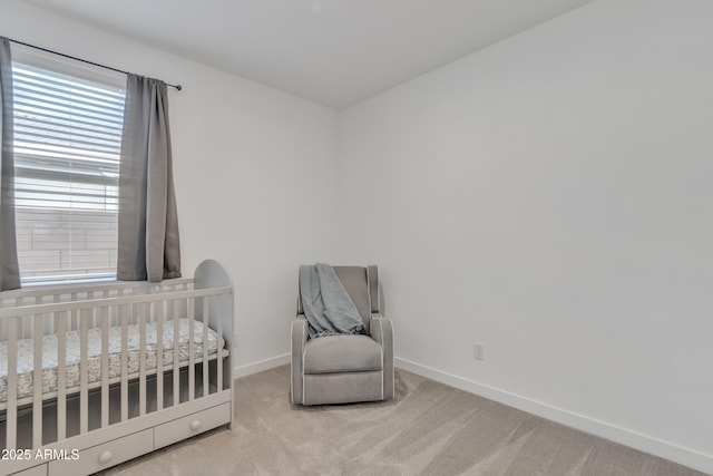 carpeted bedroom with a crib and baseboards