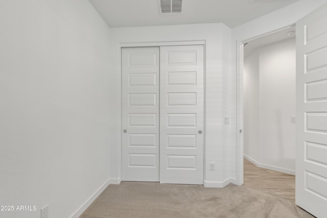 unfurnished bedroom with light carpet, baseboards, visible vents, and a closet